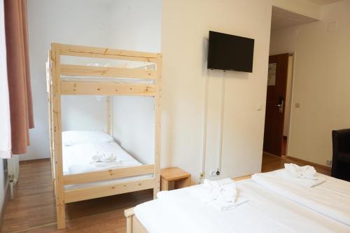a room with two beds and a tv on a wall at Hotel Kaffeemühle in Vienna