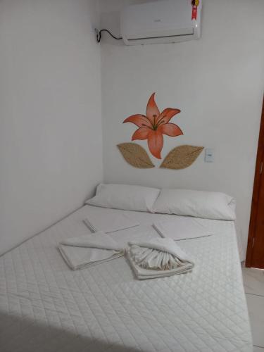 a white bed with a flower on the wall at Pousada Recanto das Flores in Praia de Moitas