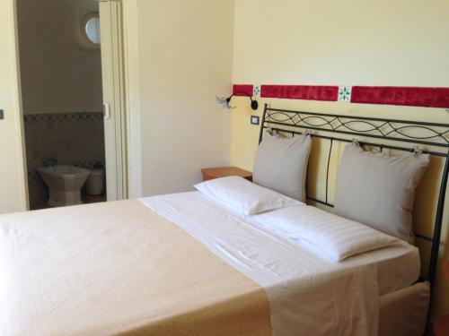 a bedroom with a large white bed with a red headboard at Giardino Di Sicilia in SantʼAgata di Militello