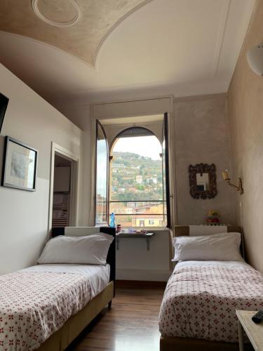 two beds in a room with a window at B&B Borghi in Como