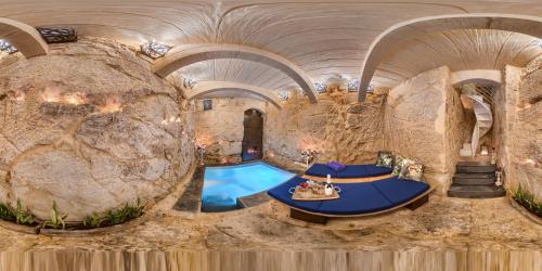 an indoor pool in a cave with a rock wall at Lulu Boutique Hotel in Żebbuġ