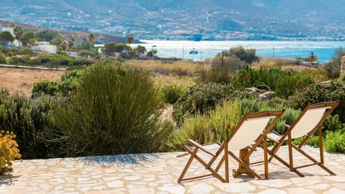 two chairs sitting on a patio overlooking the water at BLUE GREENS VILLAS in Kampos Paros