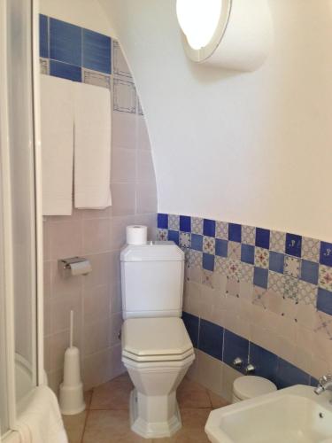 a bathroom with a white toilet and blue tiles at Giardino Di Sicilia in SantʼAgata di Militello