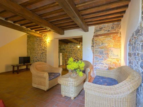 a living room with wicker chairs and a stone wall at Apartment Boccaccio by Interhome in San Donato in Poggio