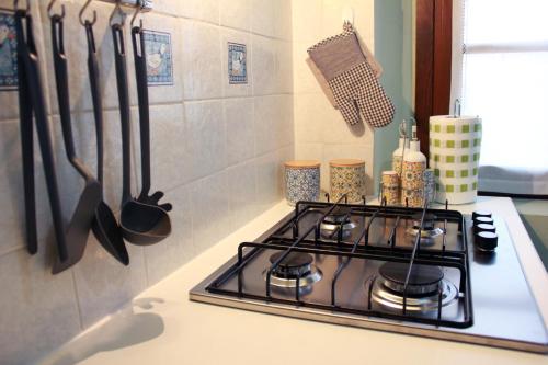 a kitchen stove with utensils on the wall at La di Morson Agriturismo in Camino al Tagliamento
