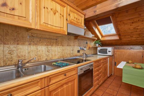 a kitchen with wooden cabinets and a sink and a stove at Mansarda alla Pineta in Giustino