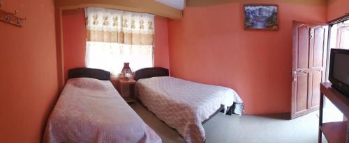 two beds in a room with orange walls at Hostal Puerto Alegre in Copacabana