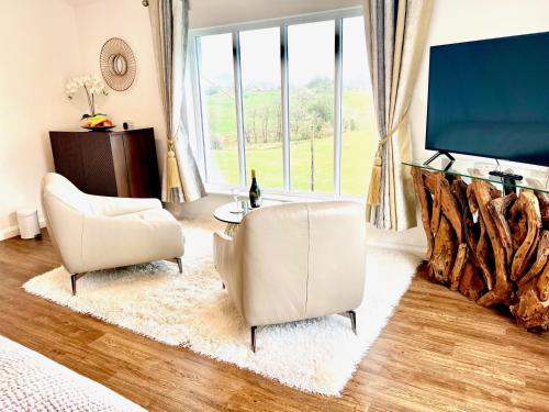 a living room with two chairs and a flat screen tv at High Grassings Country House in Ambleside