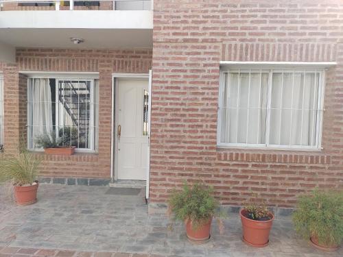 a brick house with a white door and potted plants at Ivon in Neuquén