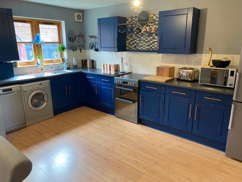 uma cozinha com armários azuis e uma máquina de lavar e secar roupa em Inverness Holiday House - 2 Bedroom em Inverness