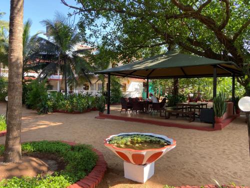 a garden with a large umbrella and a table and chairs at Dmellos Sea View Home in Candolim