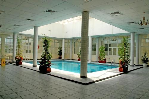 a swimming pool in a building with potted plants at Basma Residence Hotel Apartments in Sharjah