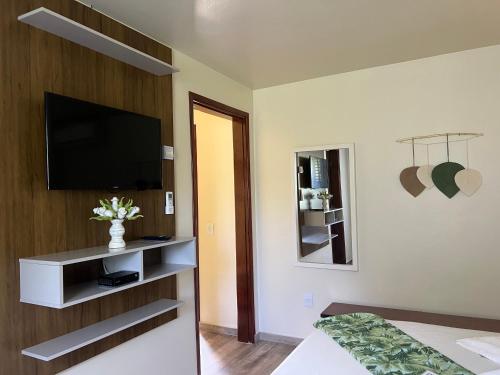 a hotel room with a television and a bed at Pousada Penedo in Penedo