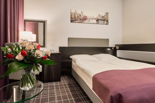 a hotel room with a bed and a vase of flowers at Sky Business Hotel in Legnica
