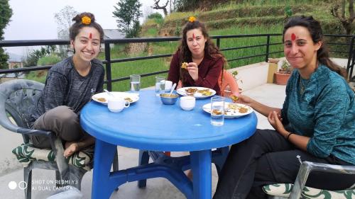 three women sitting around a blue table eating food at Patlekhet Eco Farmhouse in Dhulikhel