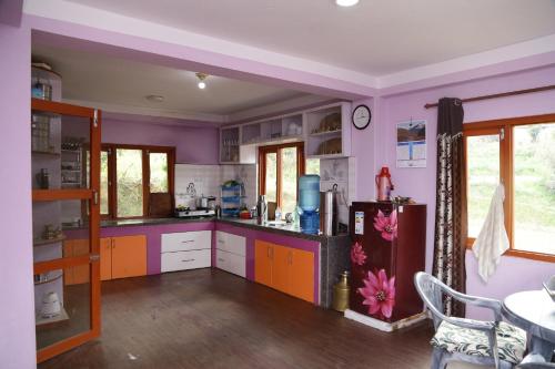 kuchnia z różowymi i pomarańczowymi szafkami oraz stołem w obiekcie Patlekhet Eco Farmhouse w mieście Dhulikhel
