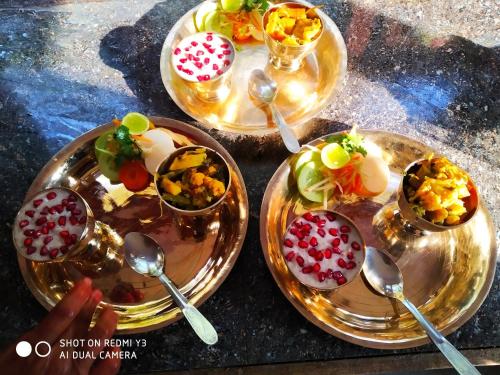 three plates of food on a table with spoons at Patlekhet Eco Farmhouse in Dhulikhel