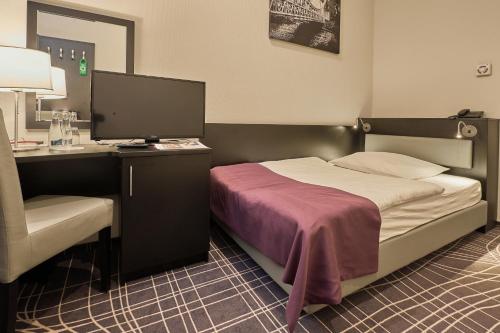 a bedroom with a bed and a desk with a computer at Sky Business Hotel in Legnica