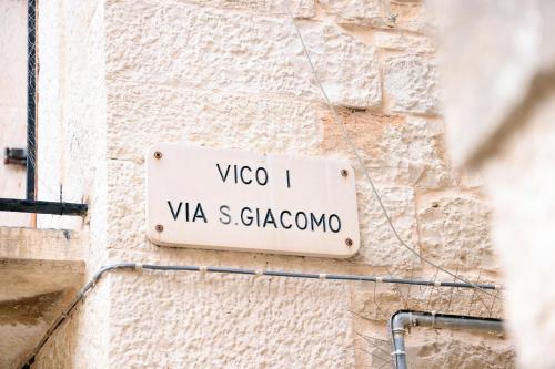 a street sign on the side of a stone wall at Le Stanze di Maria-Ingresso Autonomo Maria's Rooms-Indipendent Entrance in Giovinazzo