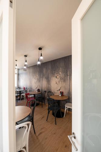 a dining room with tables and chairs and a wall at Guesthouse diWINE in Merano