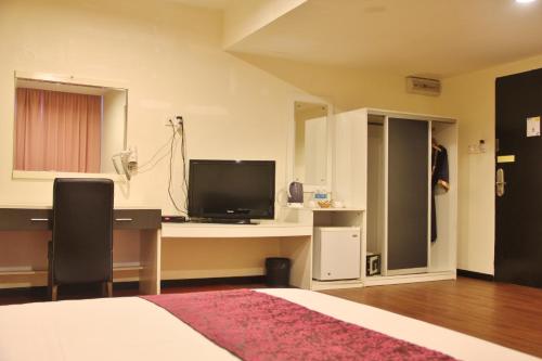 a bedroom with a bed and a desk with a television at Prince Hotel in Tawau