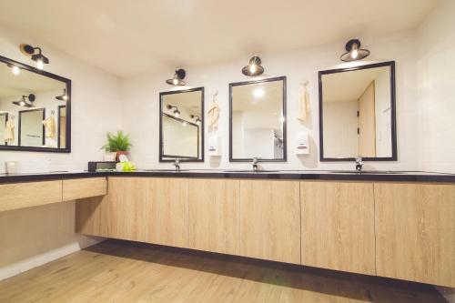 a bathroom with three sinks and three mirrors at Ahiruyah Guesthouse in Kaohsiung