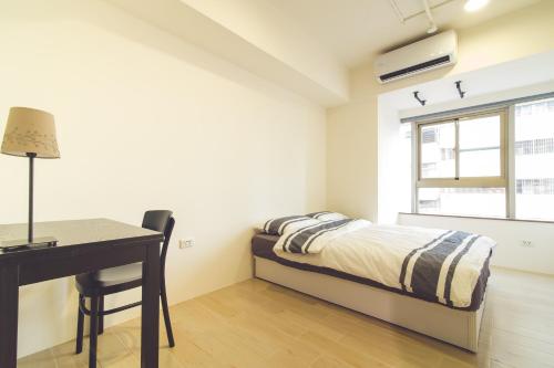 a bedroom with a bed and a desk and a window at Ahiruyah Guesthouse in Kaohsiung