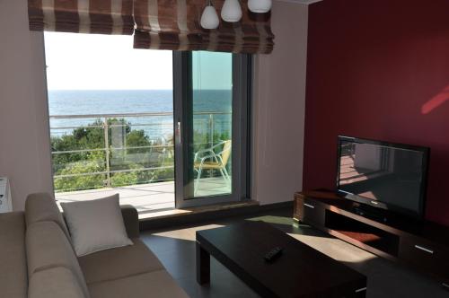a living room with a couch and a television and a balcony at Promenada28pl - Apartamenty z widokiem na morze in Międzyzdroje