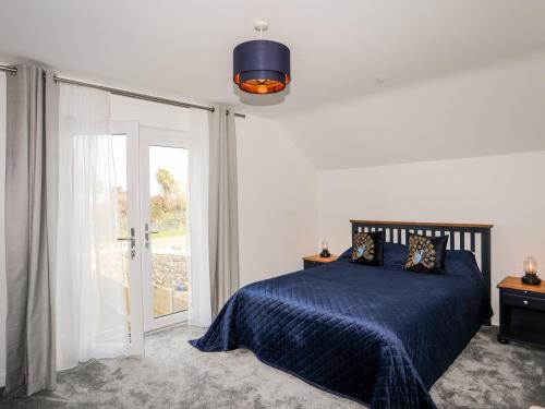 a bedroom with a blue bed and a sliding glass door at Y Ty Pren in Brynteg