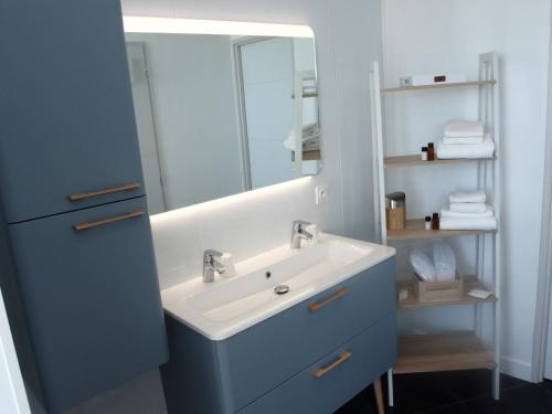 La salle de bains est pourvue d'un lavabo et d'un miroir. dans l'établissement Bleu Mer Duplex & Suites, à Saint-Cyprien