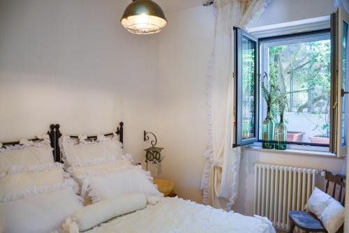 a bedroom with a bed with white pillows and a window at Cortebbianca in Fasano