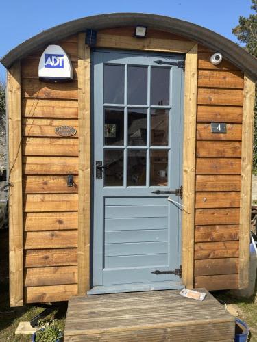 a wooden out house with a blue door at Shepherd's Hut at St Anne's - Costal Location in Plymouth