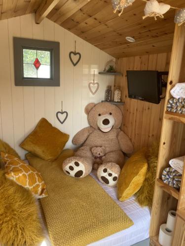 um urso de peluche sentado numa cama num quarto em Shepherd's Hut at St Anne's - Costal Location em Plymouth