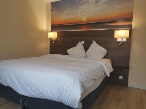 a bedroom with a large white bed with two pillows at Hotel Albert II Oostende in Ostend