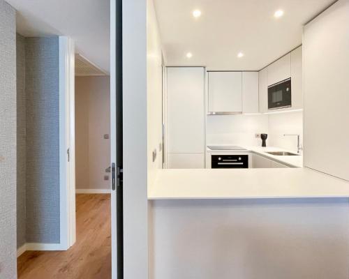a kitchen with white cabinets and a door leading into a room at Acta The Avenue in Porto