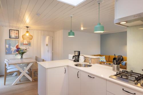 a kitchen with white cabinets and a table in a room at Center Parcs Vossemeren in Lommel