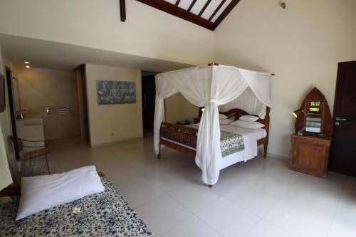 a bedroom with a bed with a canopy at Frangipani Beach Hotel in Lovina