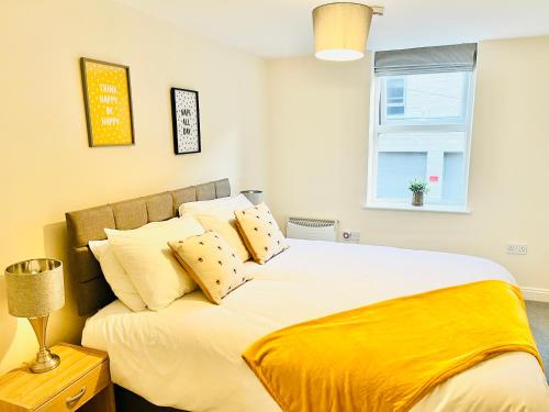 a bedroom with a large bed with yellow sheets and a window at Ilkley Apartment with Parking in Ilkley