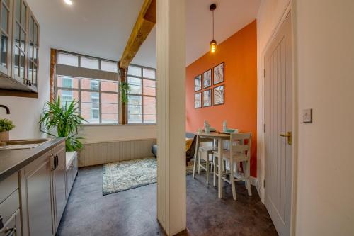 a kitchen with an orange wall and a table with chairs at Lovely Central 1 Bed Apartment Sleeps 2 plus 1 in Sheffield