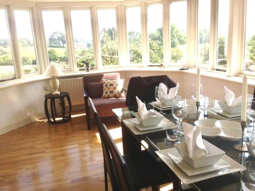 a dining room with a table and chairs and windows at High Grassings Country House in Ambleside