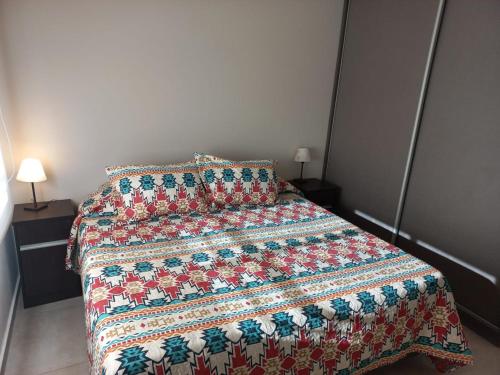a bedroom with a bed with a quilt on it at DEPARTAMENTOS MORENO in San Rafael