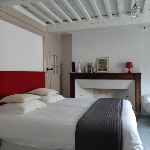 a bedroom with a large white bed and a fireplace at La Paresse en Douce in Tours-sur-Meymont