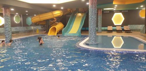 a swimming pool with a slide and people in the water at Kraljevi Cardaci 9D 12- Sunny view in Kopaonik