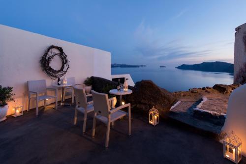 a dining room with a view of the ocean at night at Enalion Suites in Oia