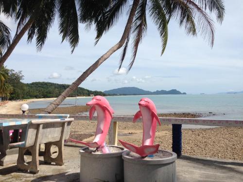 two pink flamingos in front of a table on the beach at Sea Breeze House, Naiplao Beach in Khanom
