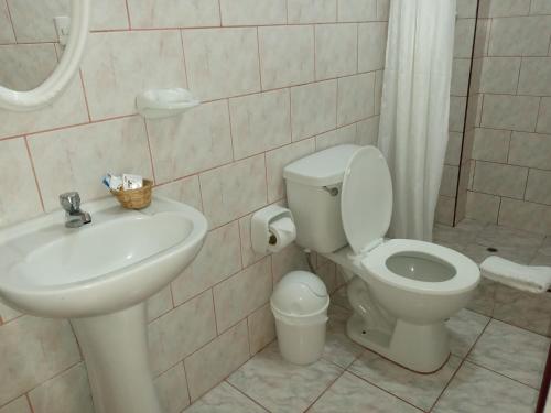 a white bathroom with a toilet and a sink at Inkas Land in Machu Picchu