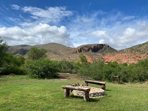 a bench in a field with mountains in the background at Baviaanskloof Laaste Kamp - Wild Bush Camping in Sandvlakte