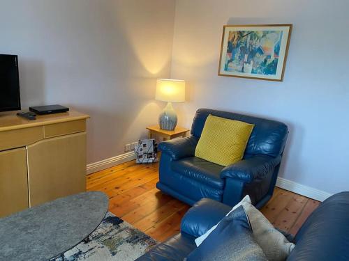 a living room with a blue couch and a yellow pillow at Sea View, 1st Floor, Harbour Mill, Westport Quay in Westport