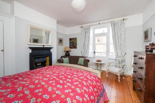 a bedroom with a red bed and a fireplace at Seaview Villa - Norfolk Cottage Agency in Sheringham