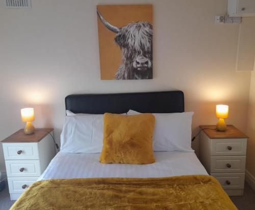 a bedroom with a bed with two lamps and a cow painting at Delphi Lodge in Donaghmore